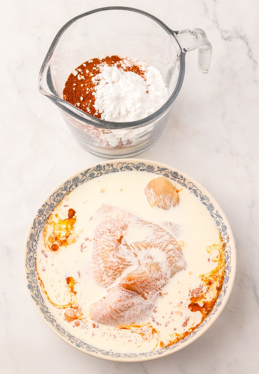 buttermilk coated pieces of chicken in a shallow bowl