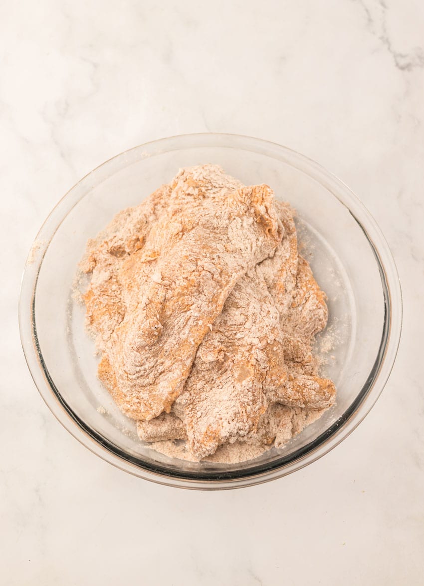 breaded pieces of marinated chicken in a glass mixing bowl