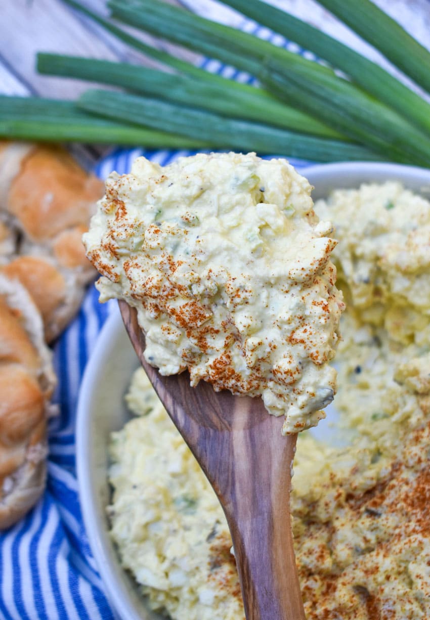 a wooden spoon holding up a scoop of deviled egg salad