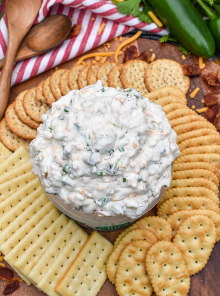 a plastic tub filled with grillo's dill pickle dip surrounded by crackers