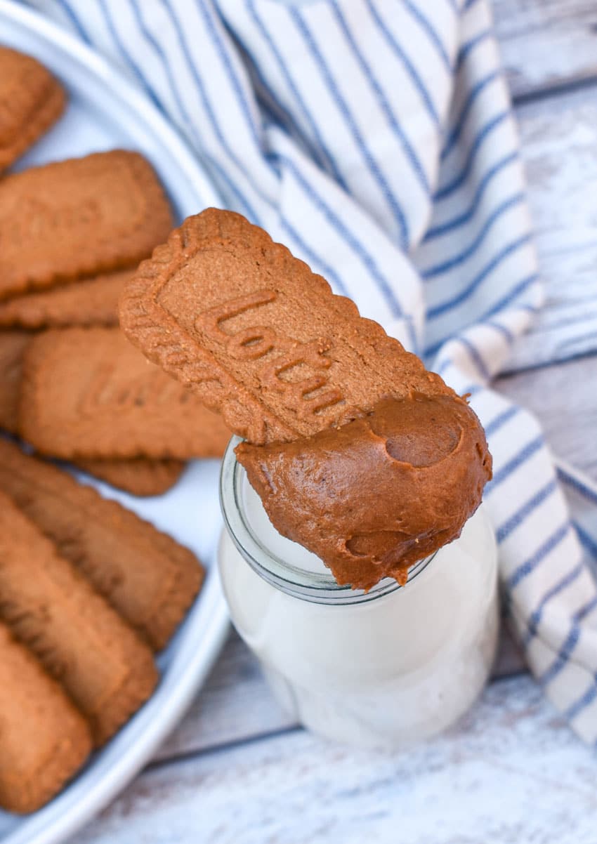 homemade cookie butter on a biscoff cookie resting on the edge of a glass of milk