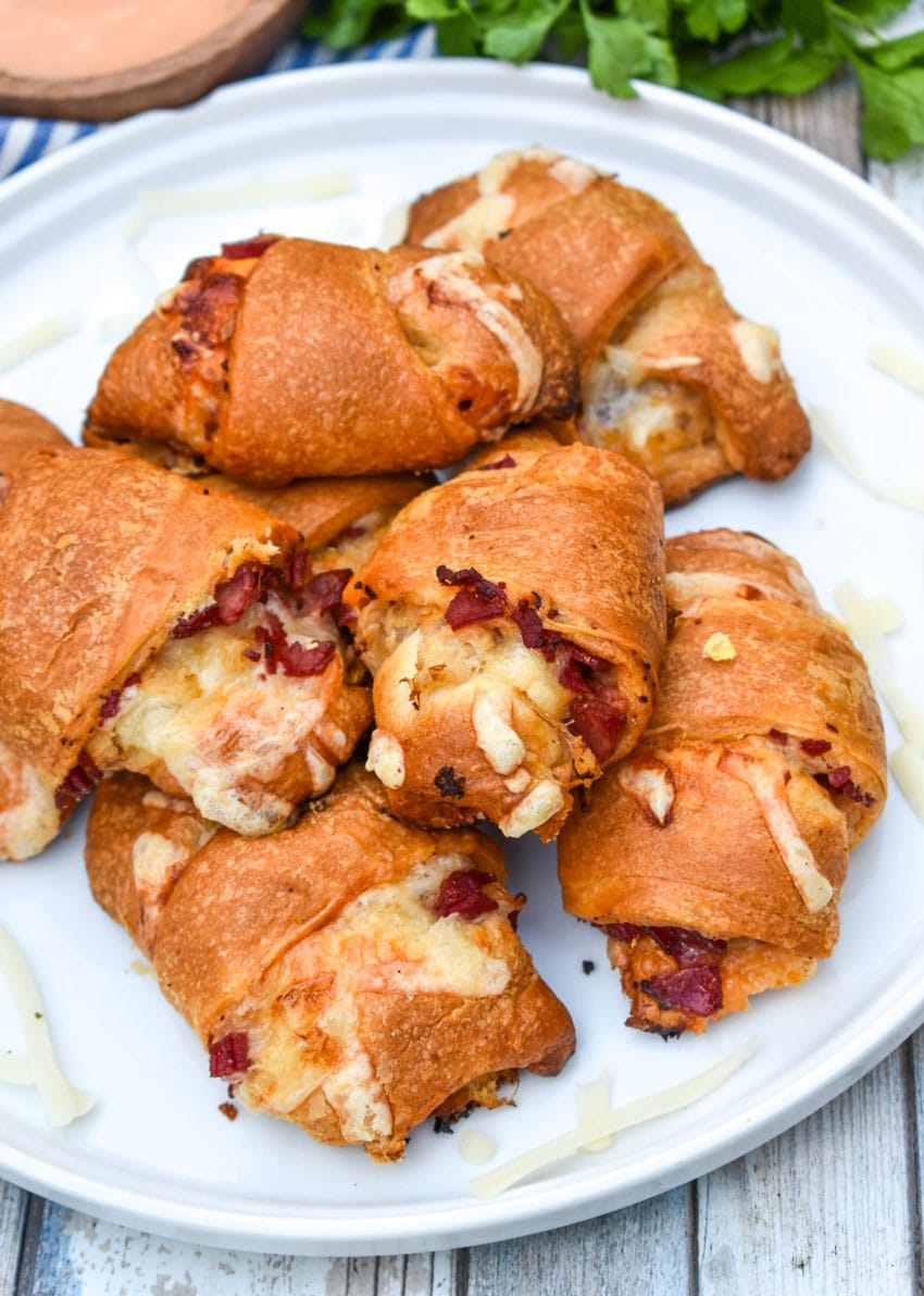 reuben crescent rolls stacked on a white serving plate