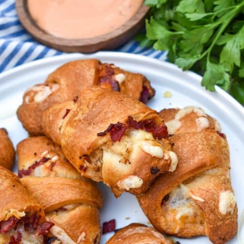 reuben crescent rolls stacked on a white serving plate