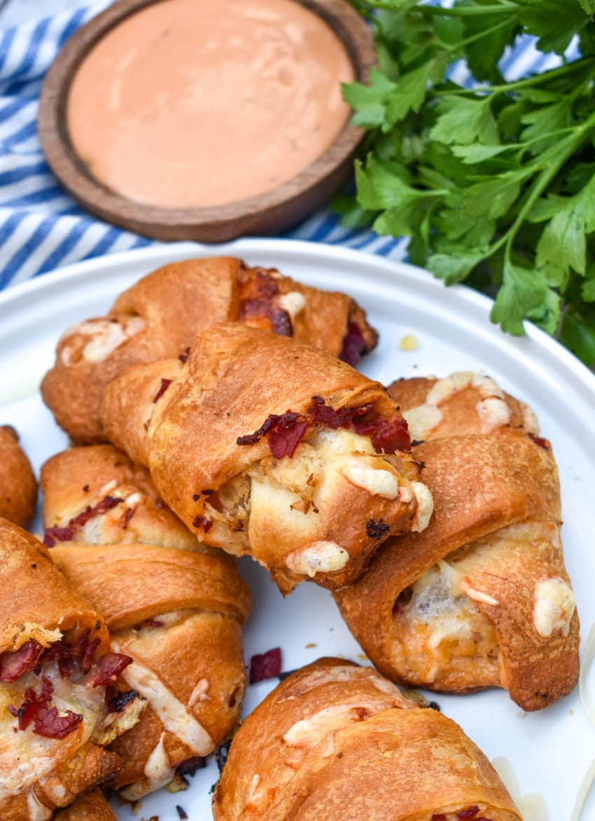 reuben crescent rolls stacked on a white serving plate