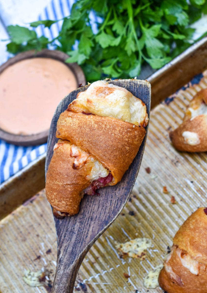 a wooden spatula holding up a baked reuben crescent roll