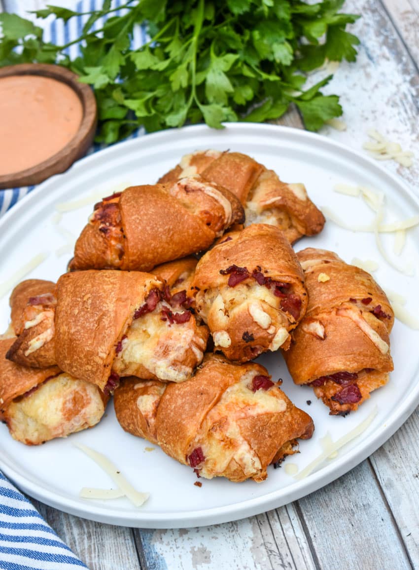 reuben crescent rolls stacked on a white serving plate