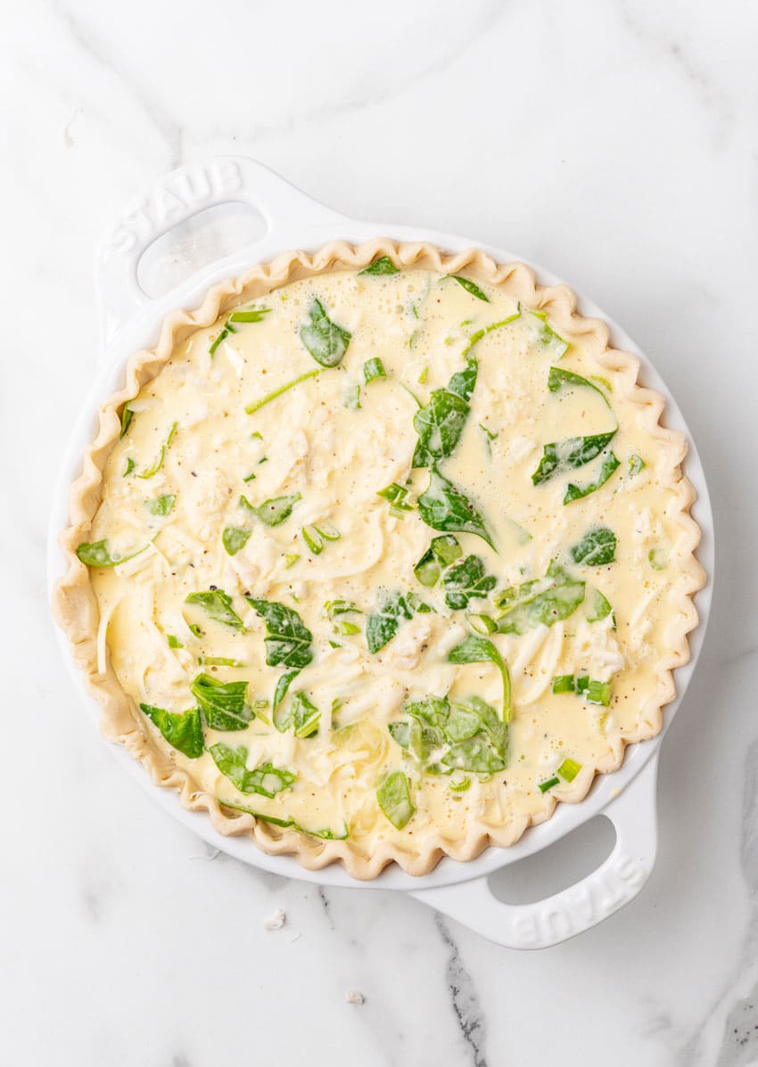 an unbaked crab quiche on a marble countertop