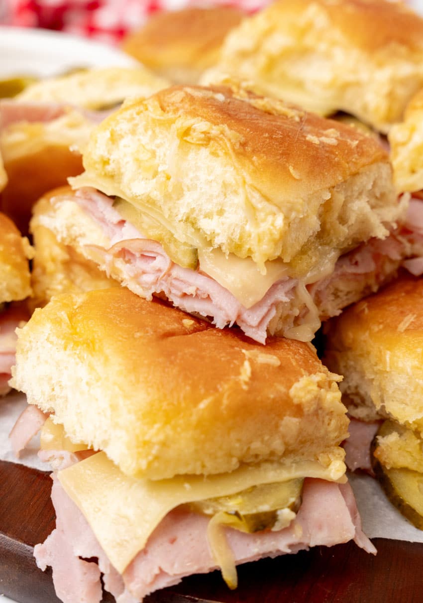 a stack of cuban style sliders on a wooden cutting board