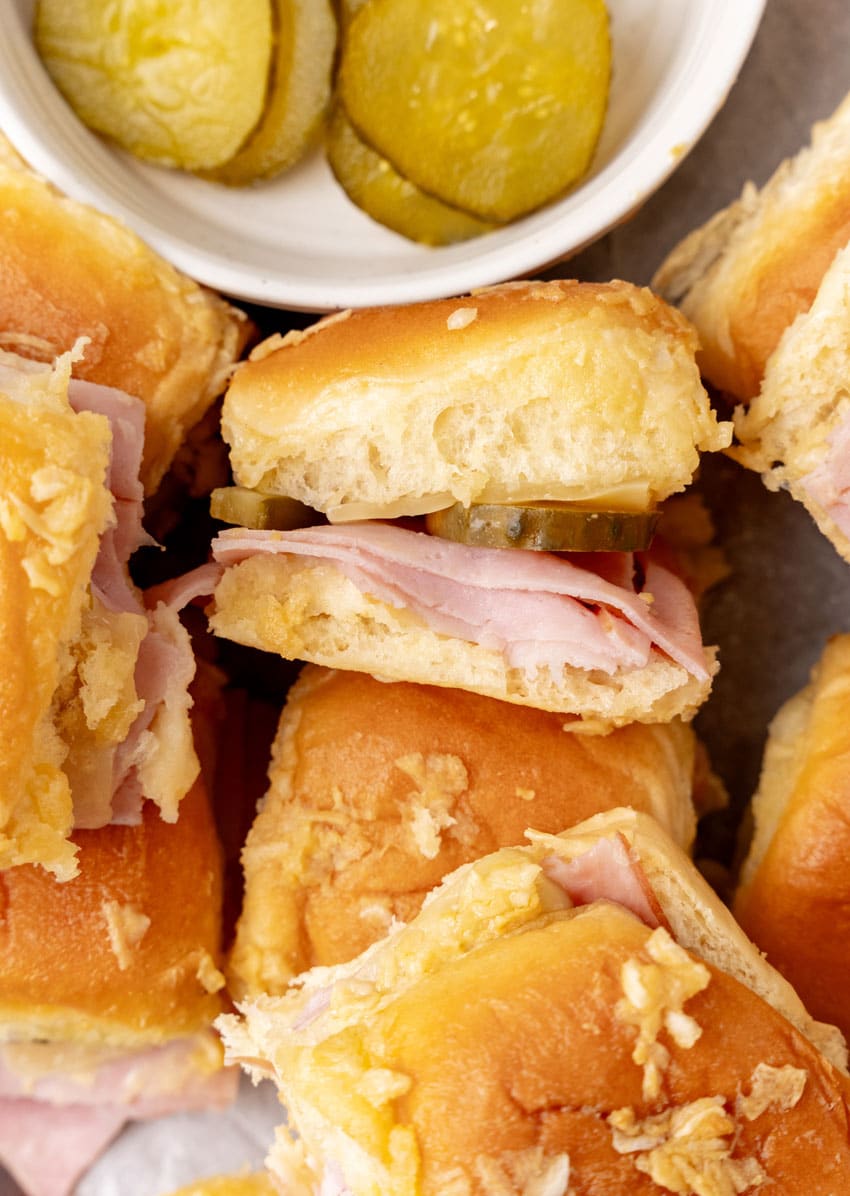 cuban style sliders on hawaiian rolls on a parchment paper lined wooden cutting board