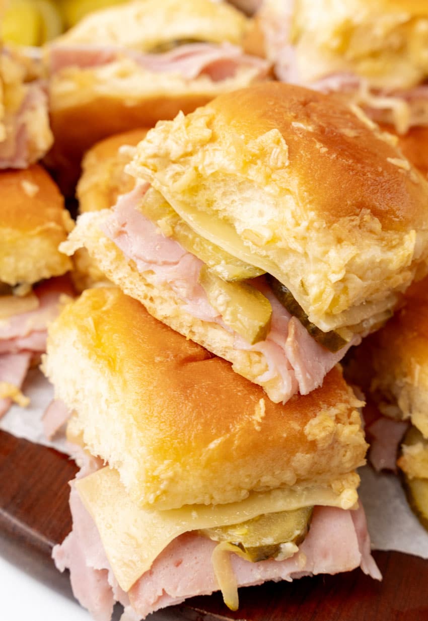 a stack of cuban style sliders on a wooden cutting board