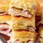 a stack of cuban style sliders on a wooden cutting board