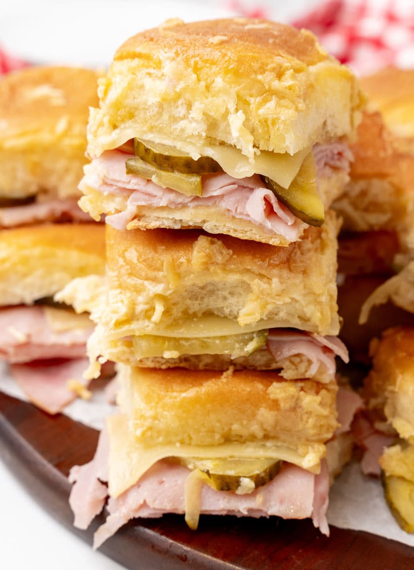 a stack of cuban style sliders on a wooden cutting board