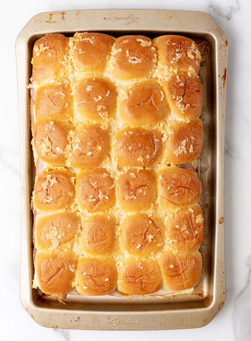 baked cuban style sliders on hawaiian rolls on a rimmed baking sheet