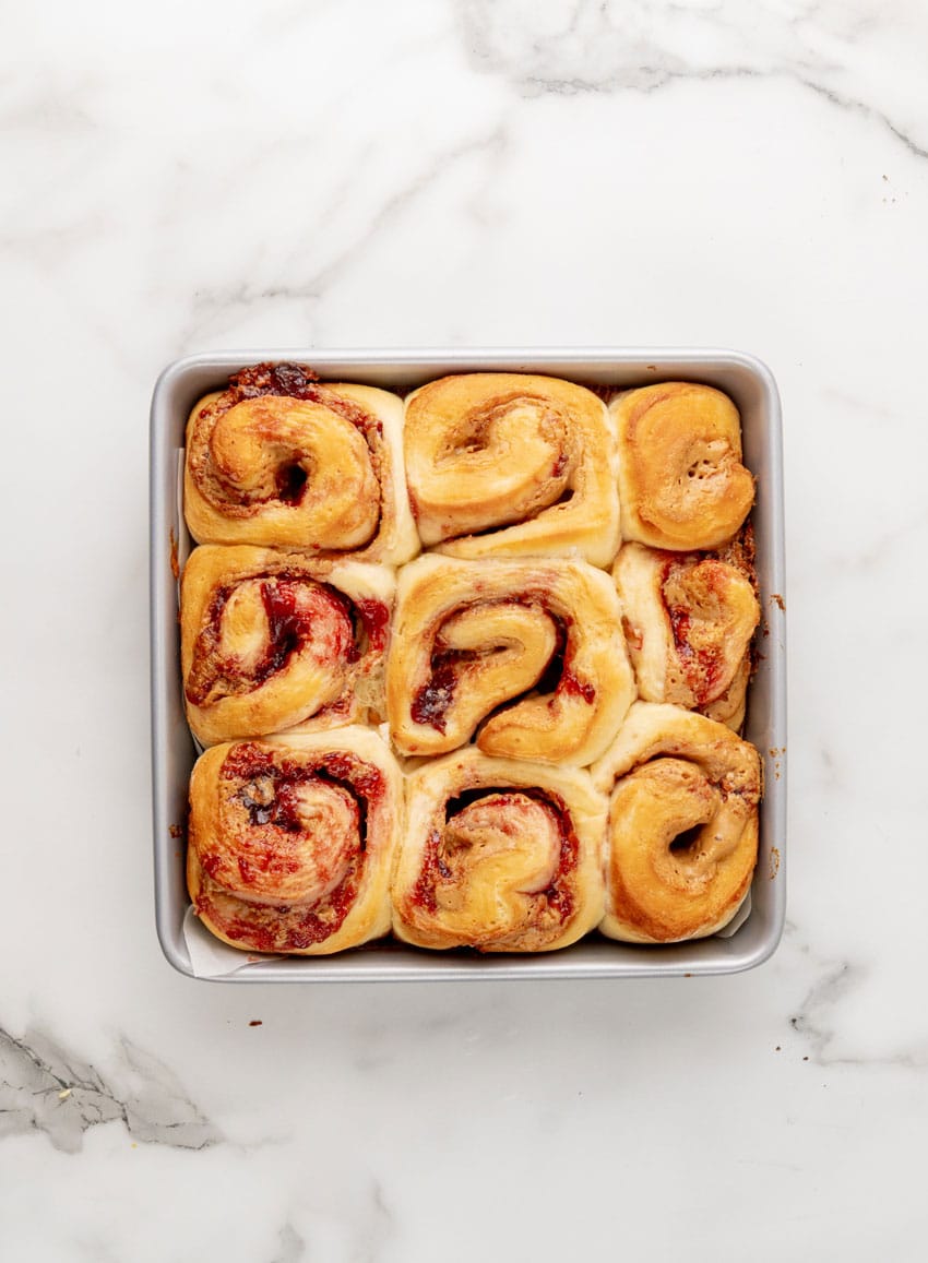 baked peanut butter and jelly sweet rolls in a parchment paper lined metal baking pan