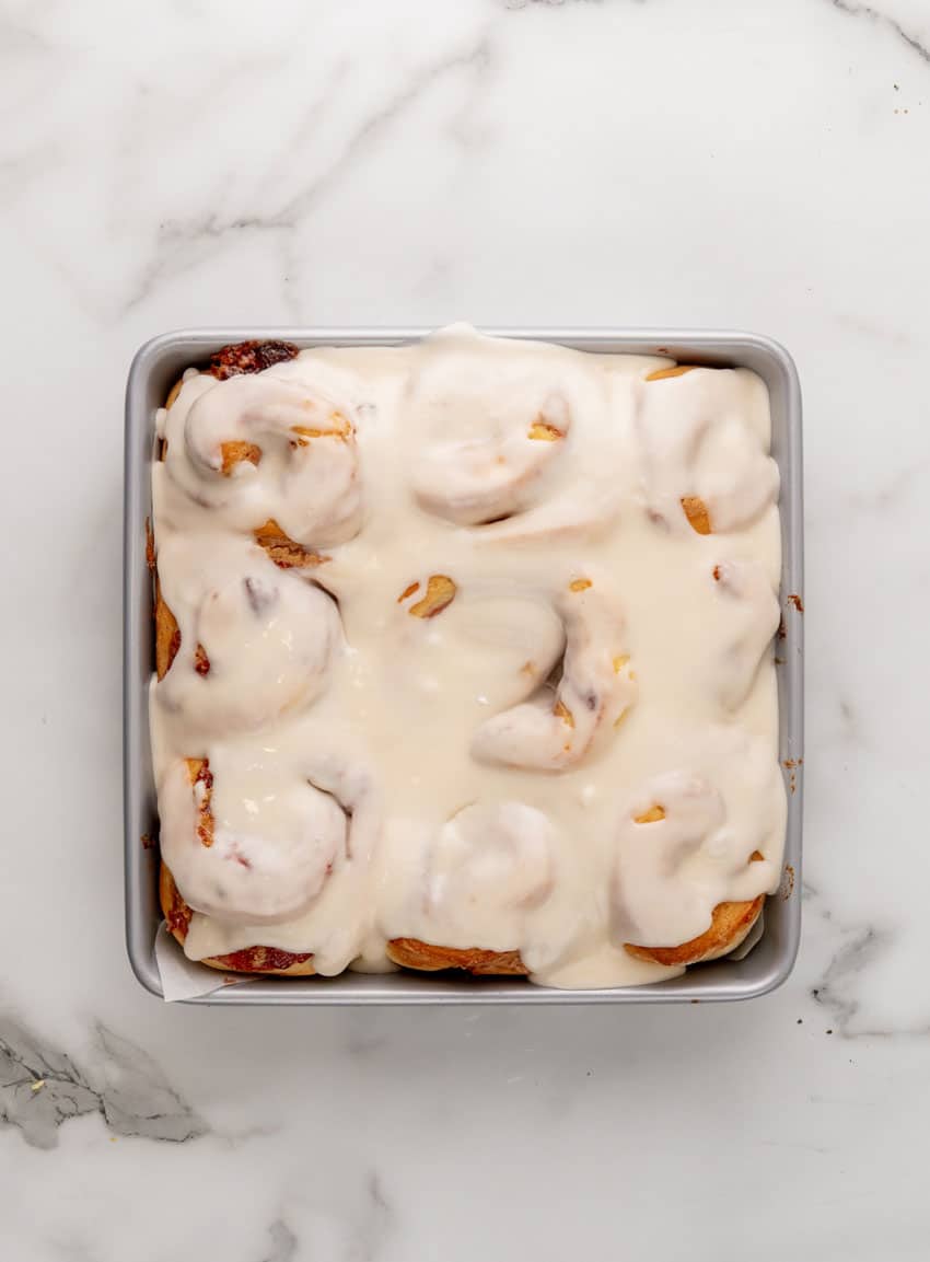 glazed peanut butter and jelly sweet rolls in a parchment paper lined metal baking pan