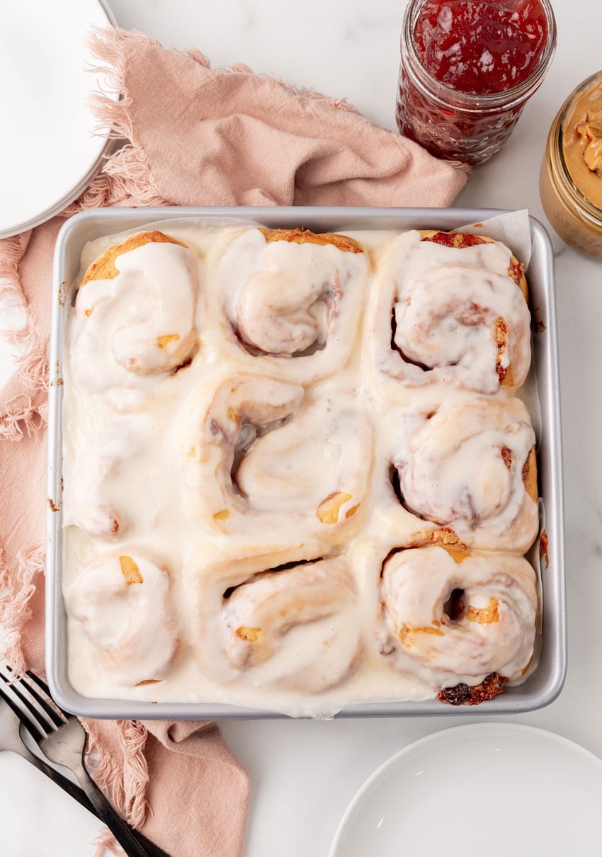glazed peanut butter and jelly sweet rolls in a parchment paper lined metal baking pan