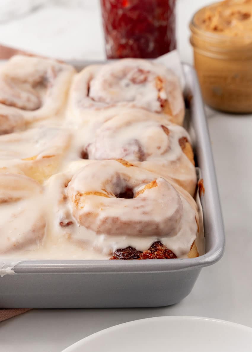 glazed peanut butter and jelly rolls in a silver baking pan