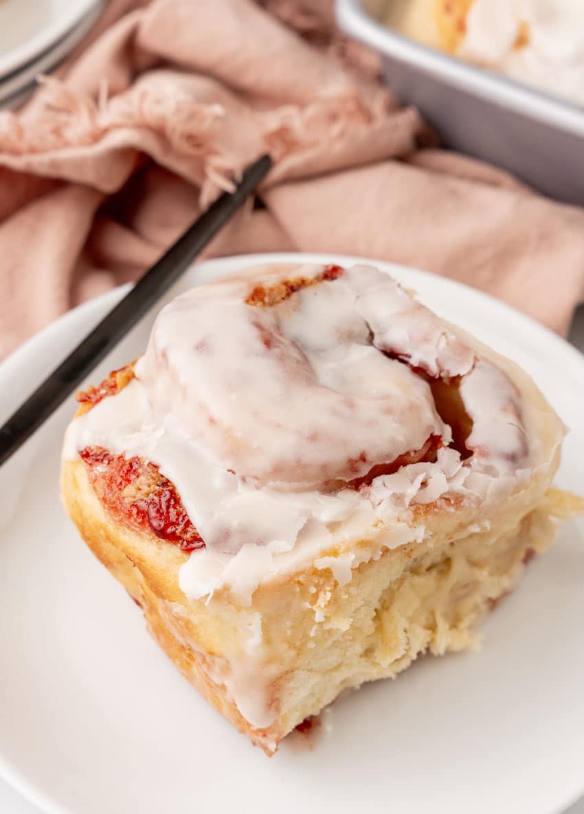 a glazed peanut butter and jelly sweet roll on a small white dessert plate