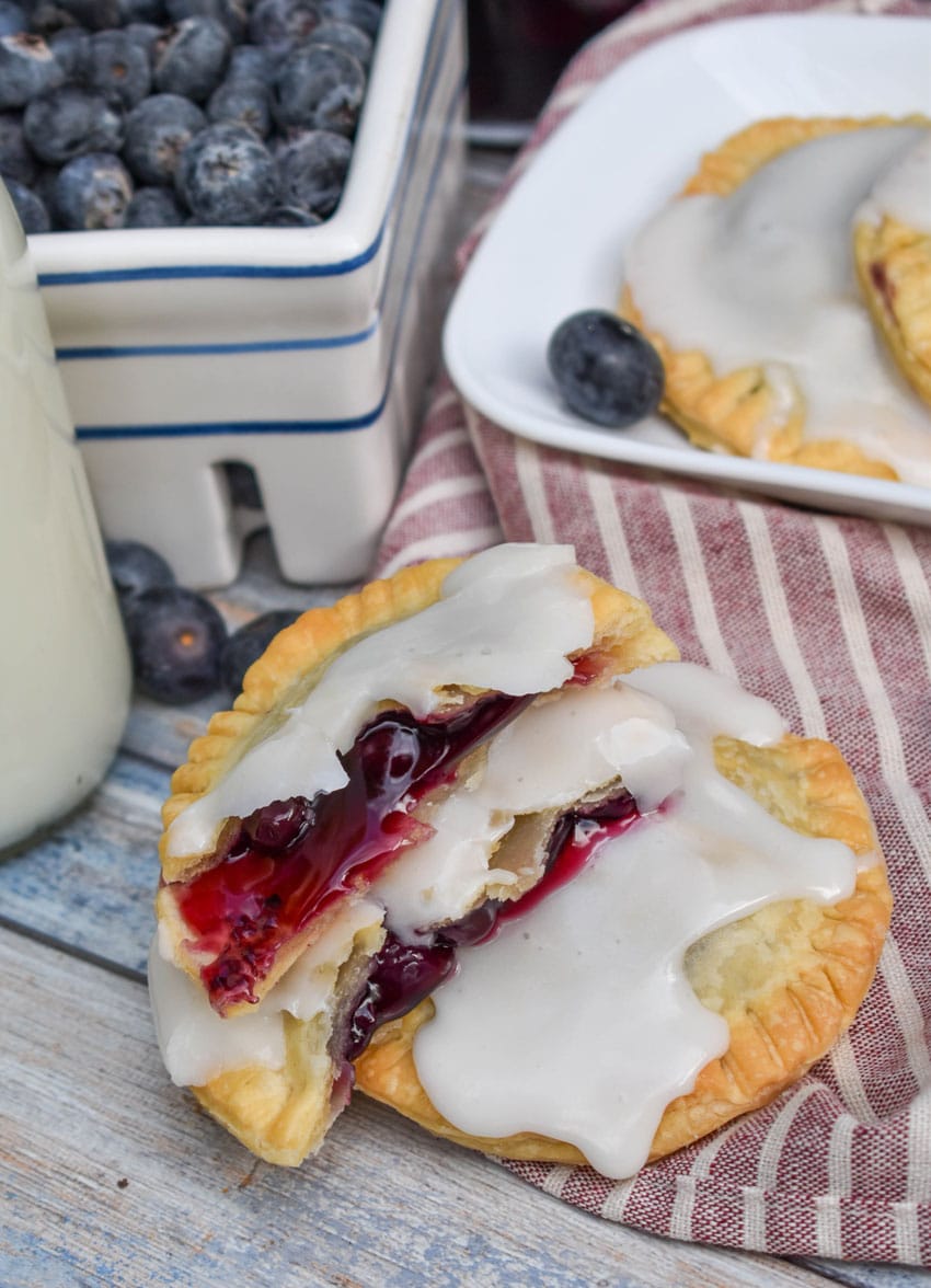 two halves of an air fried blueberry hand pie stacked on a wooden table