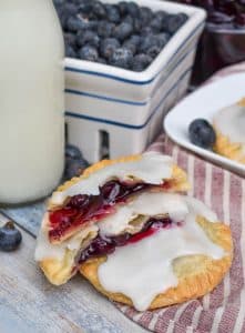 two halves of an air fried blueberry hand pie stacked on a wooden table