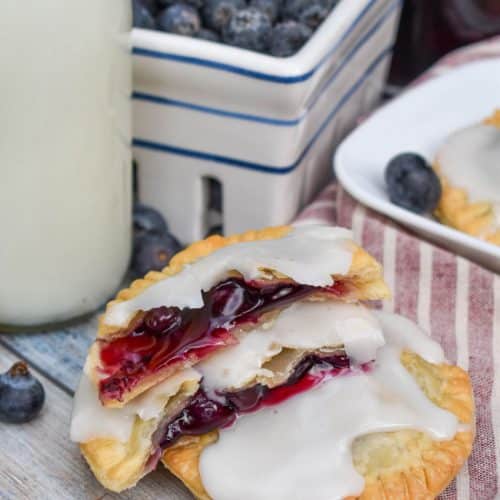 two halves of an air fried blueberry hand pie stacked on a wooden table