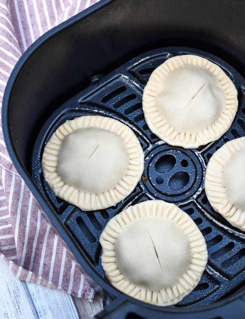 unbaked blueberry filled hand pies in the basket of an air fryer