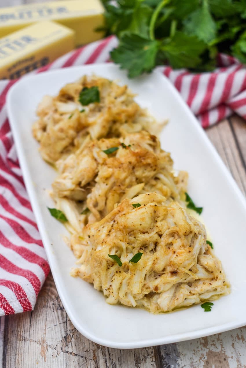 three crab bombs arranged in a row on a narrow white serving plate
