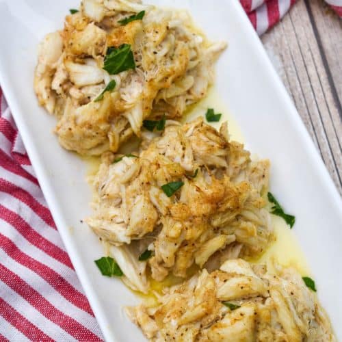 three crab bombs arranged in a row on a narrow white serving plate