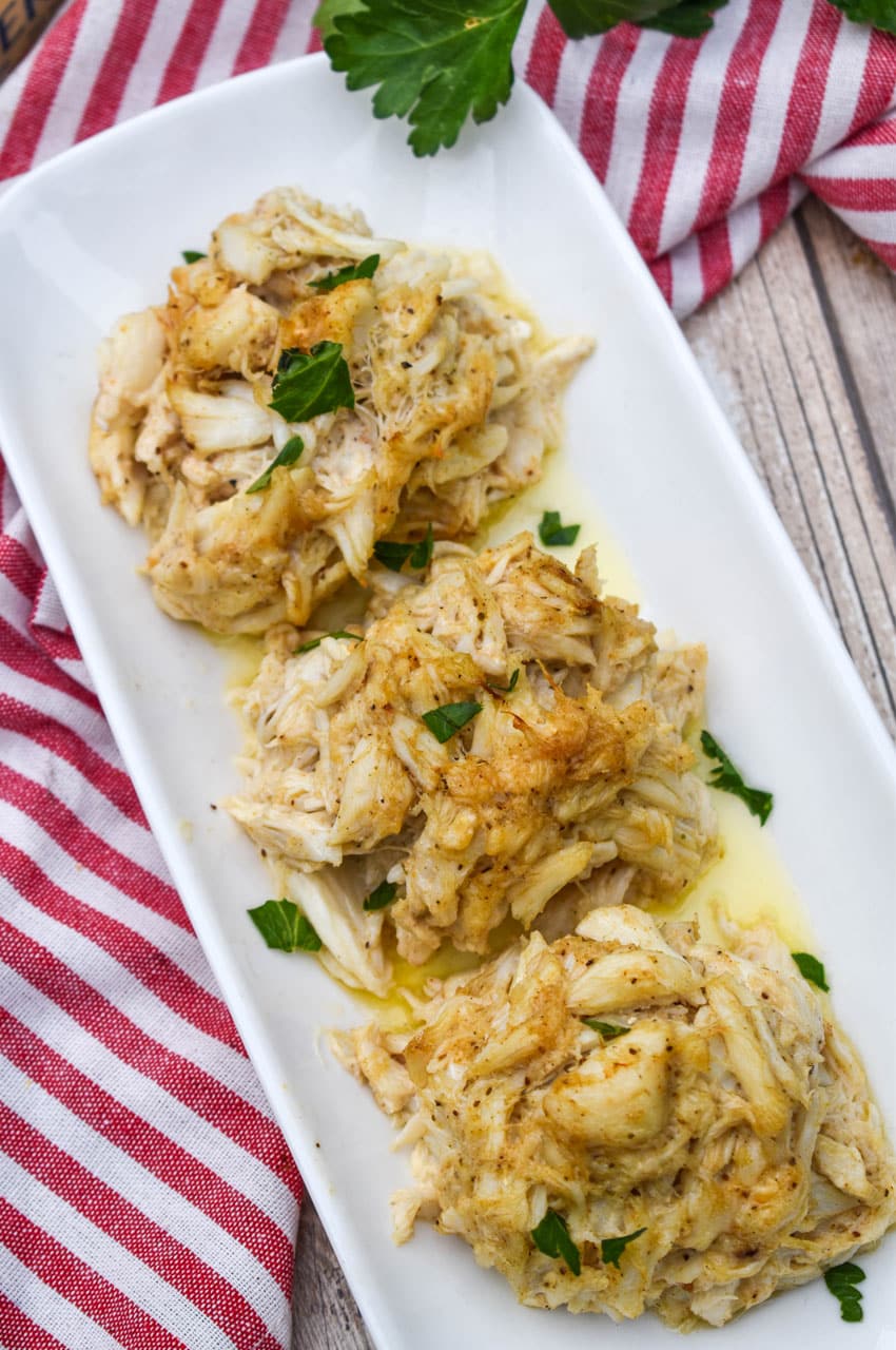 three crab bombs arranged in a row on a narrow white serving plate