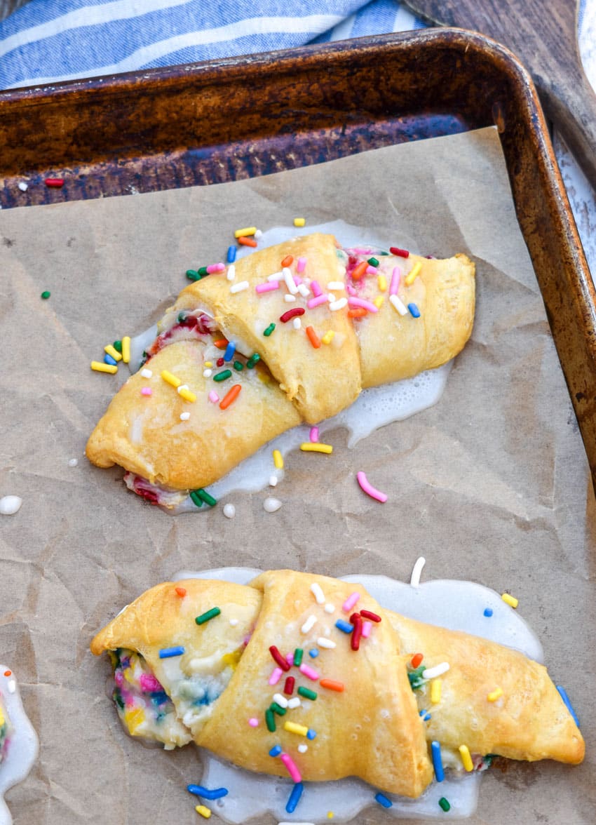 glazed funfetti crescent rolls on a parchment paper lined baking sheet