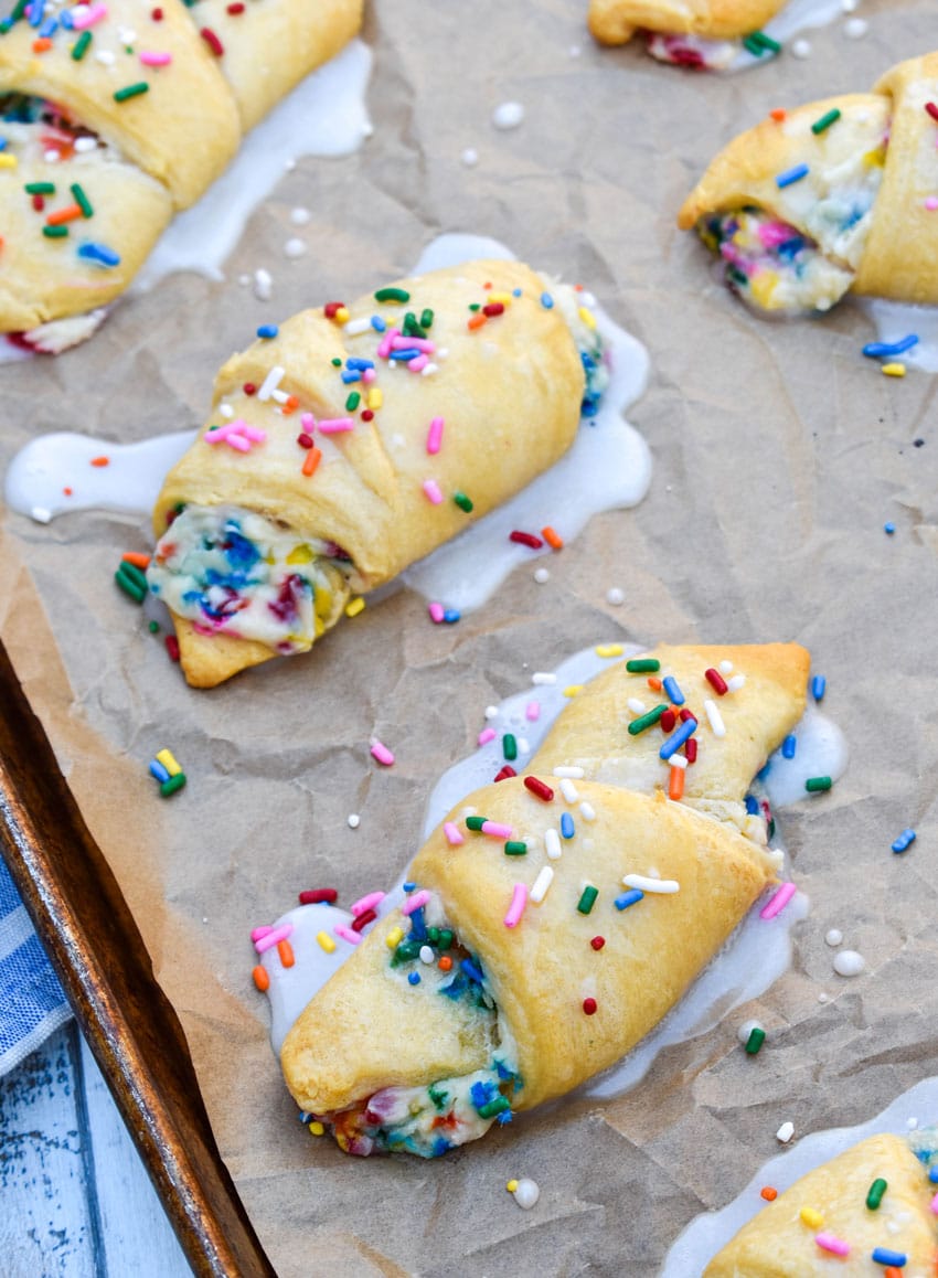 glazed funfetti crescent rolls on a parchment paper lined baking sheet
