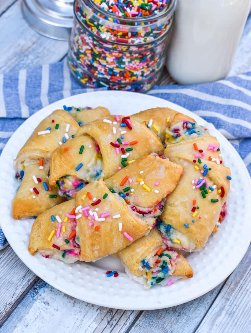 glazed funfetti crescent rolls piled on a small white plate