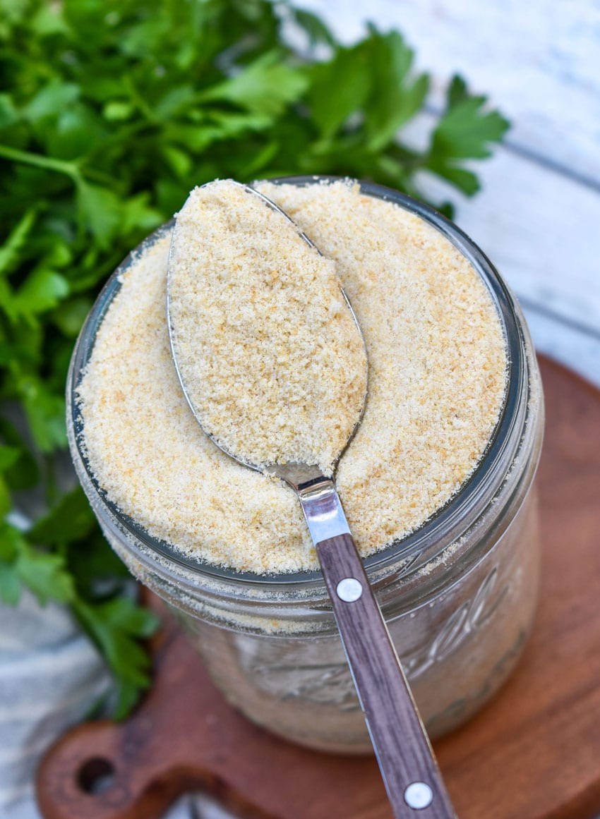 a spoon scooping homemade bread crumbs out of a small glass mason jar