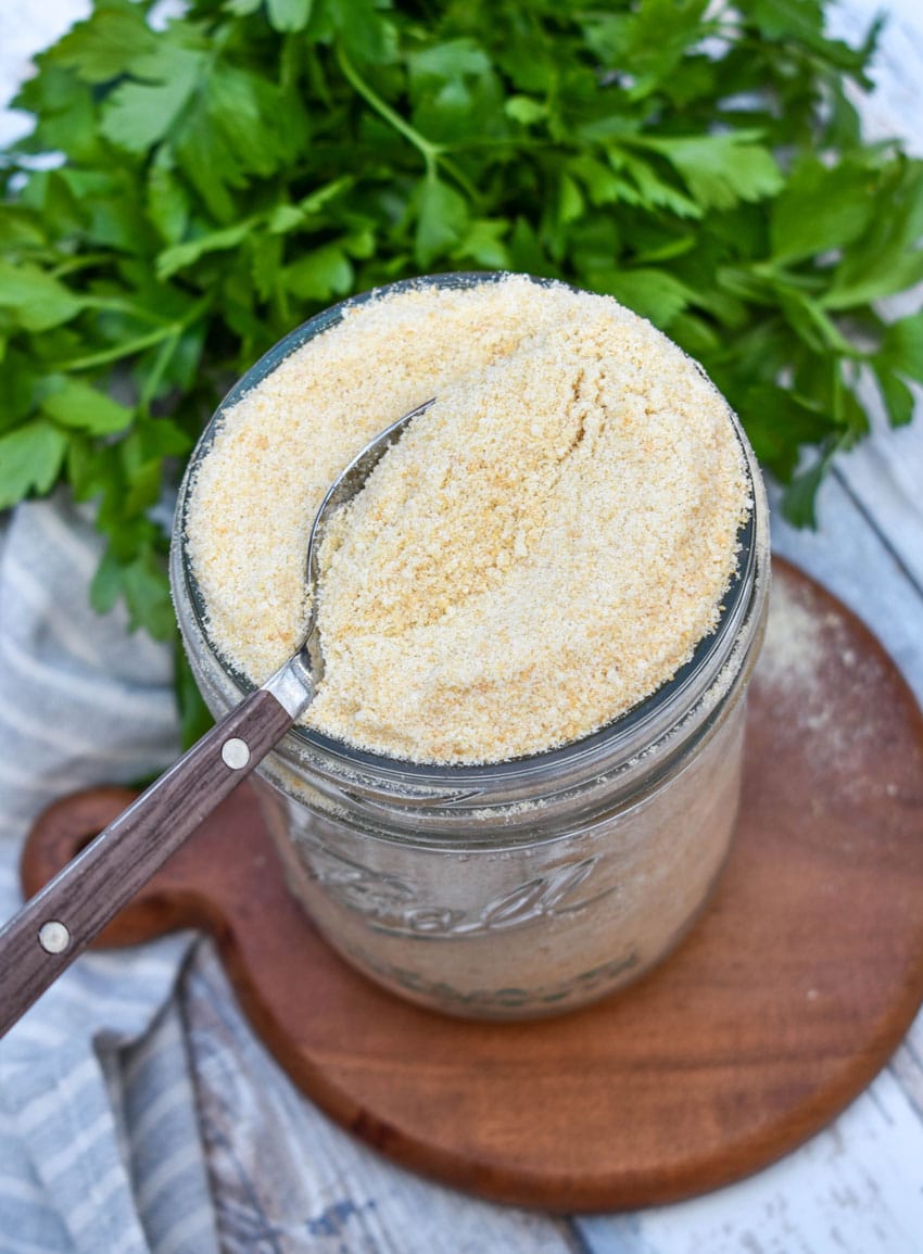 a spoon scooping homemade bread crumbs out of a small glass mason jar