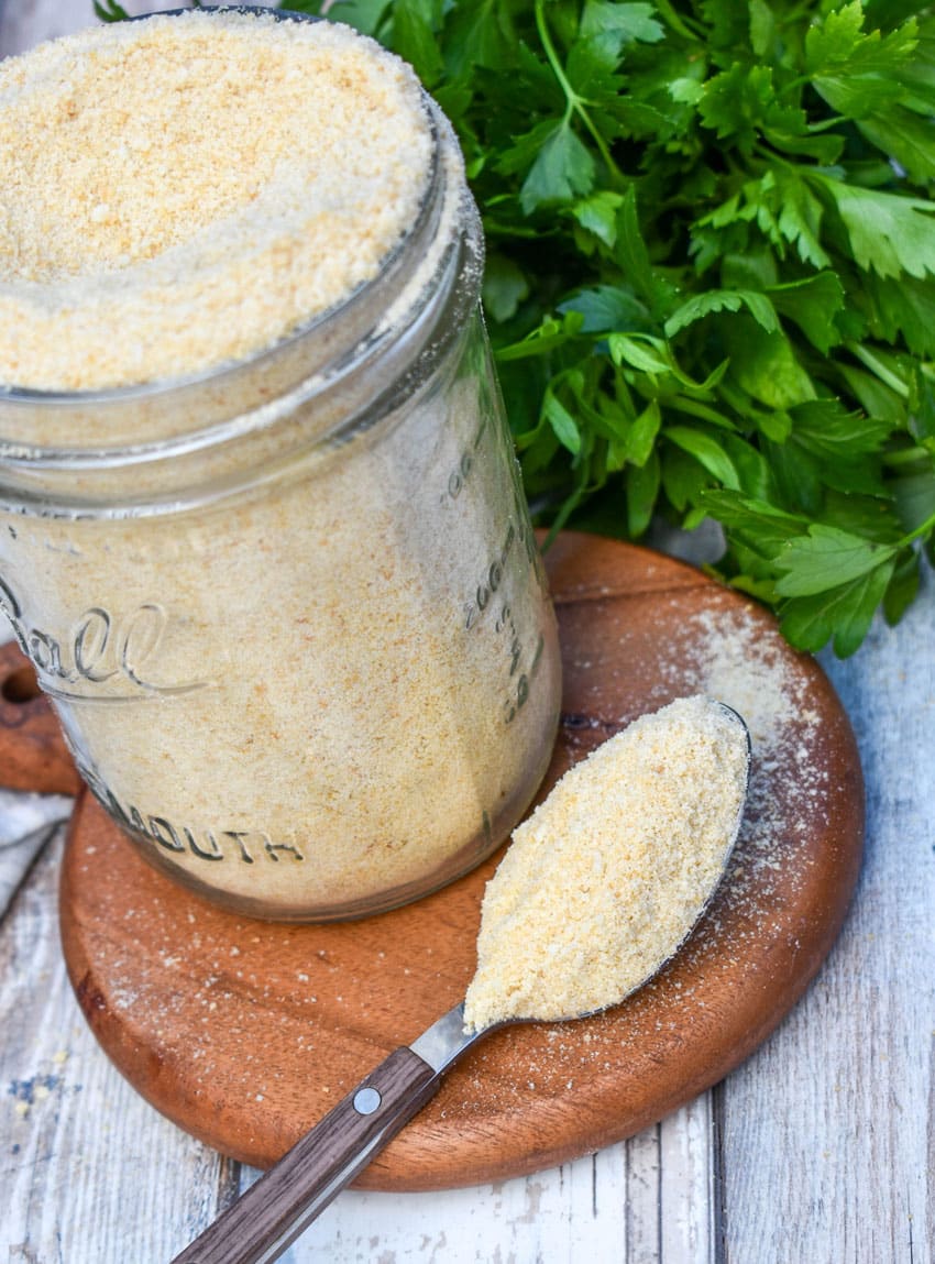 a small spoon holding a scoop of homemade bread crumbs resting on a small wooden trivet