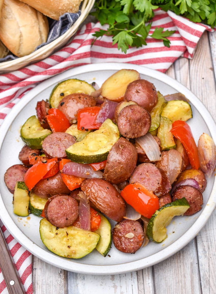 slices of kielbasa sausage and roasted vegetables on a white plate
