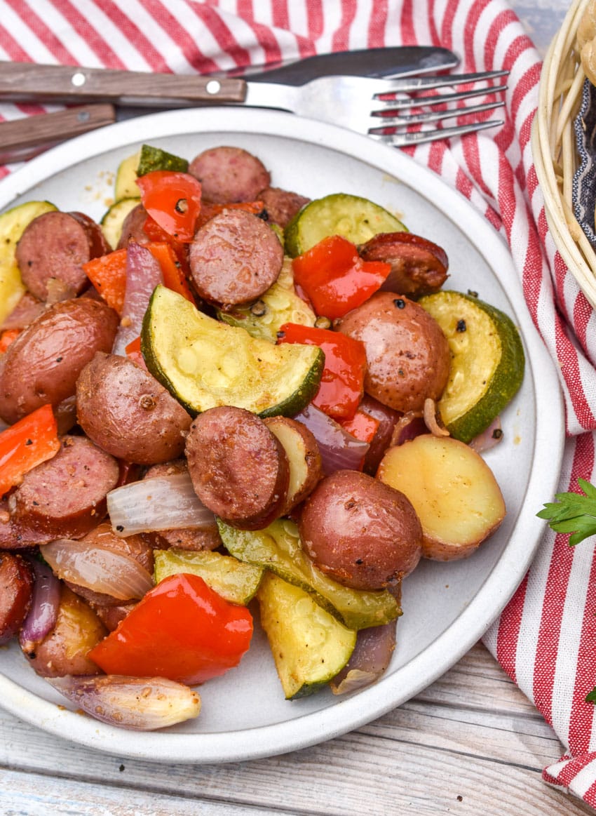 slices of kielbasa sausage and roasted vegetables on a white plate