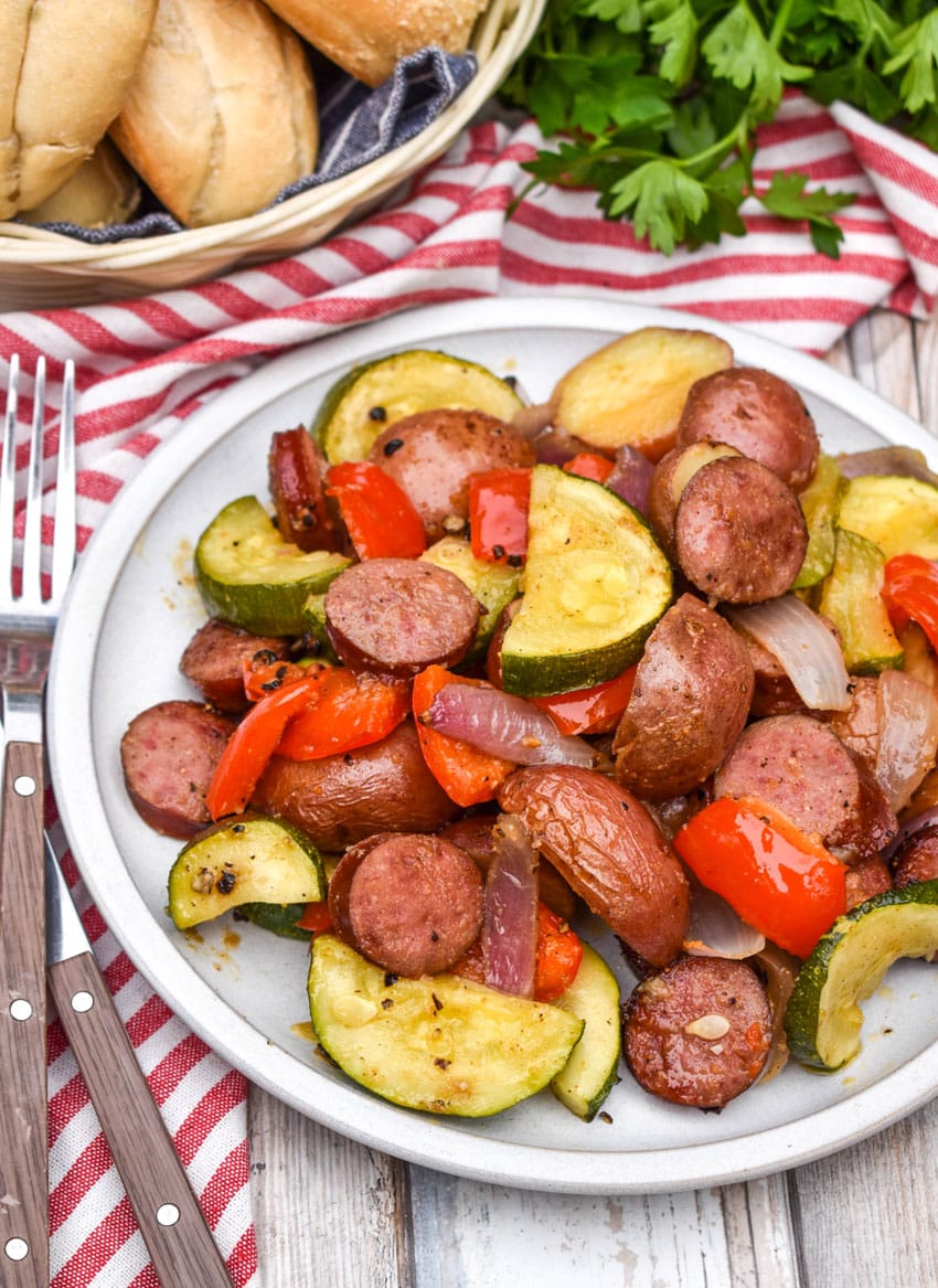 slices of kielbasa sausage and roasted vegetables on a white plate