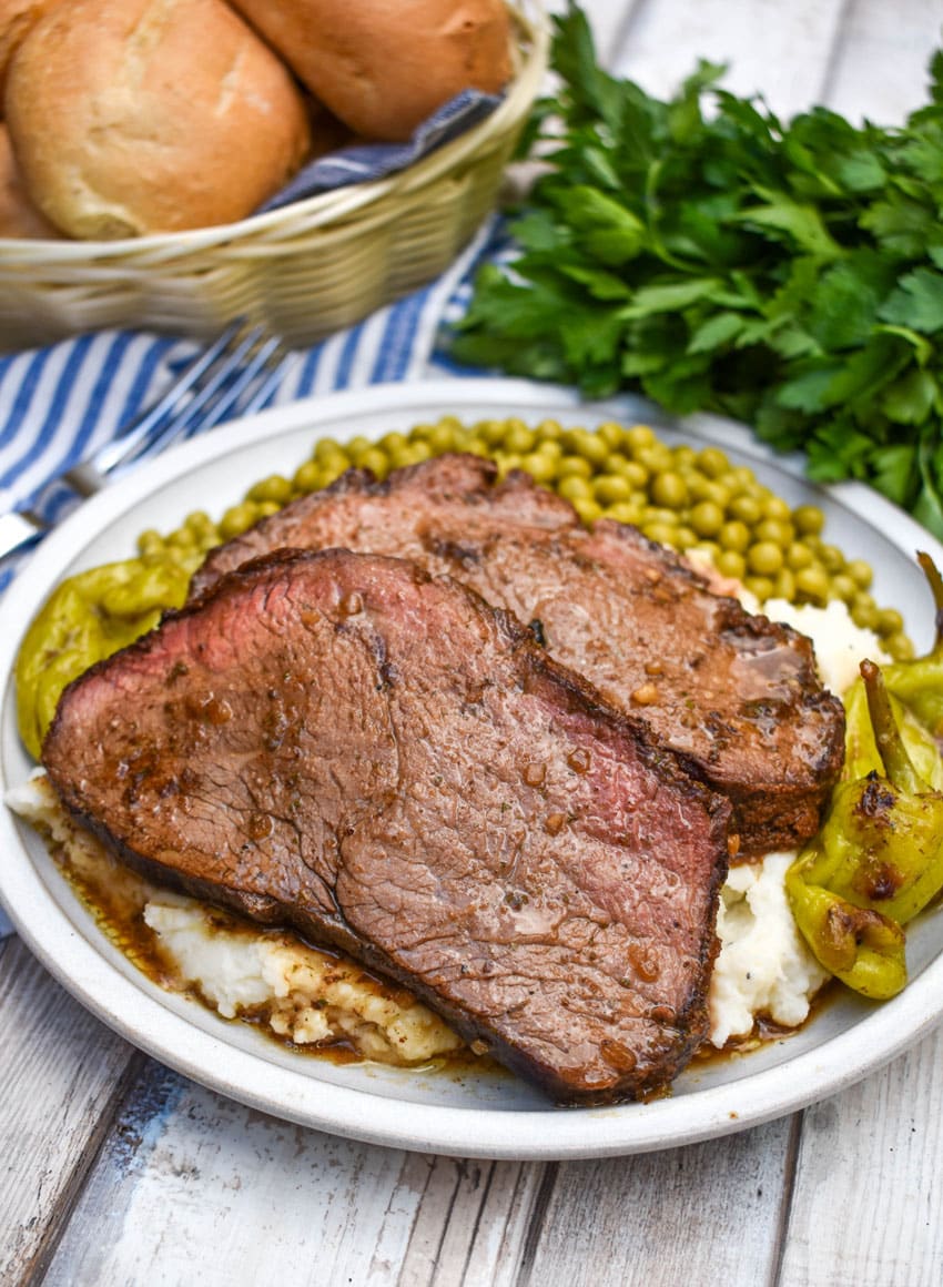 slices of smoked mississippi pot roast over mashed potatoes on a white plate