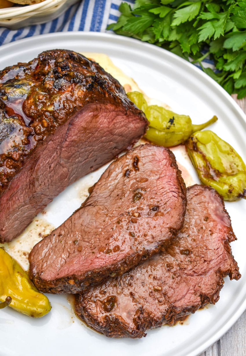 a sliced smoked mississippi chuck roast on a white serving plate