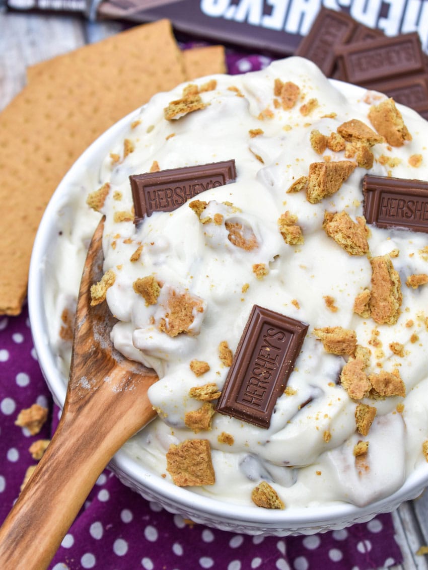 a wooden spoon scooping s'mores fluff salad out of a white serving bowl