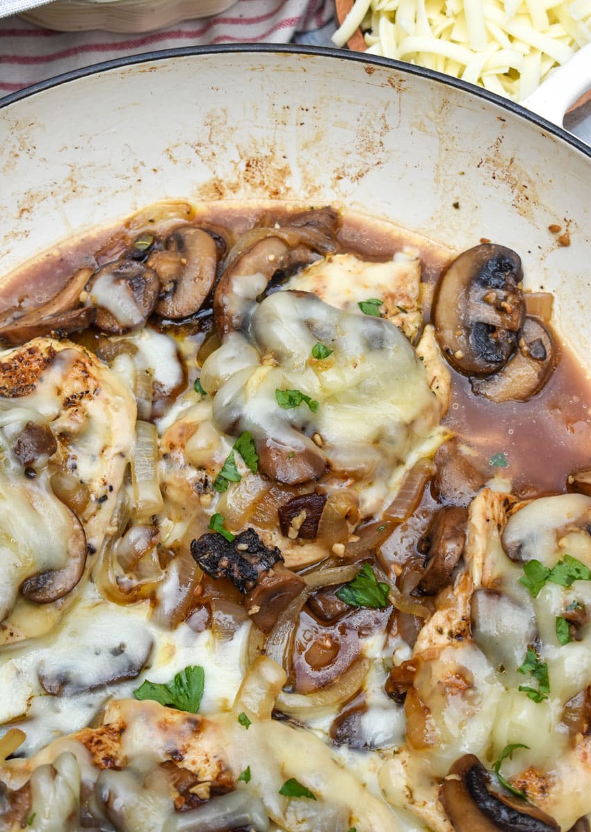 homemade cheesy smothered chicken in a large cast iron skillet