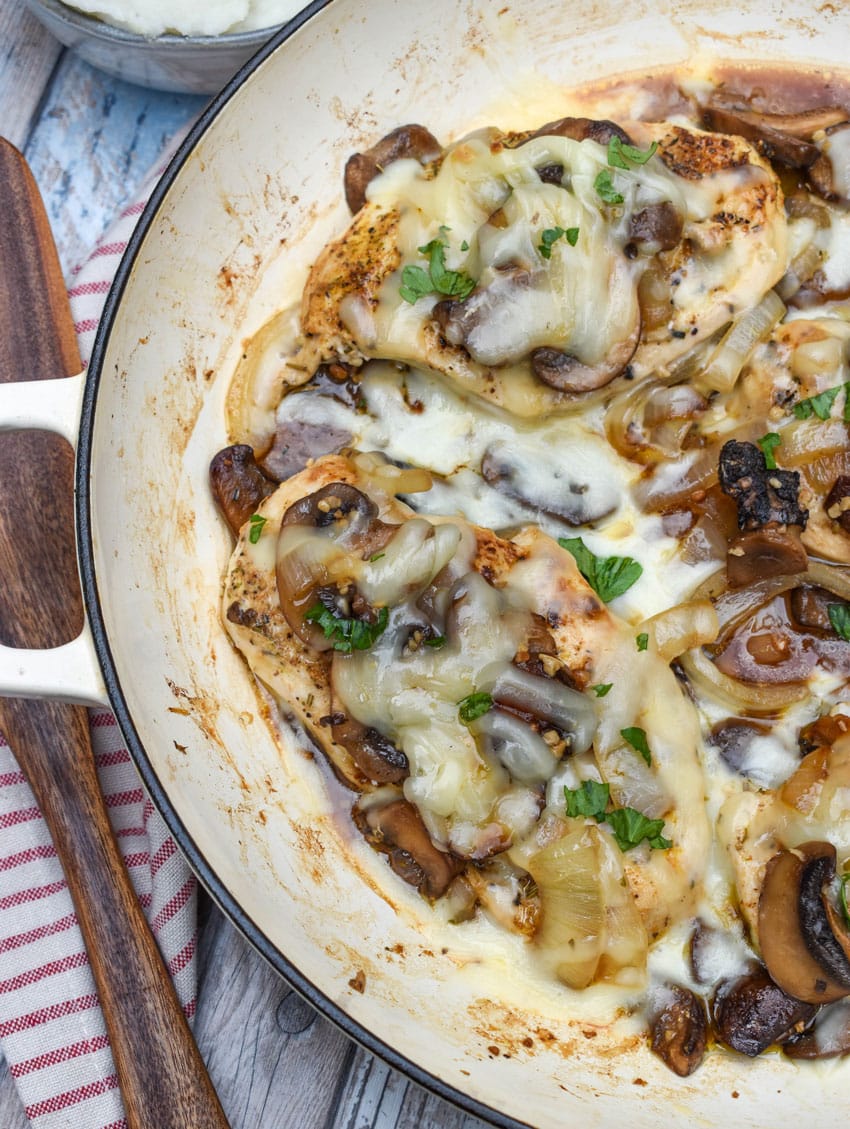 homemade cheesy smothered chicken in a large cast iron skillet