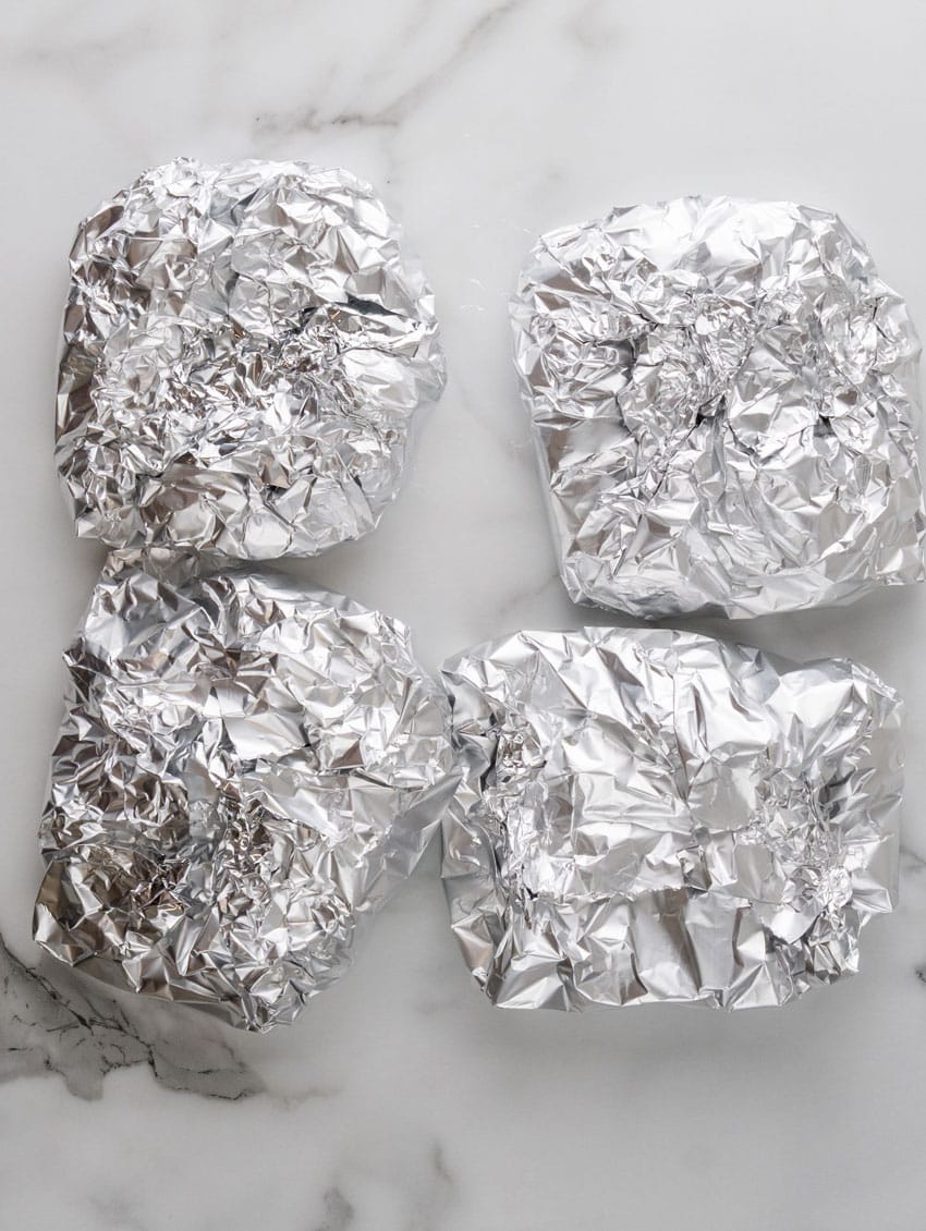 steak and potato foil packets on a marble counter top