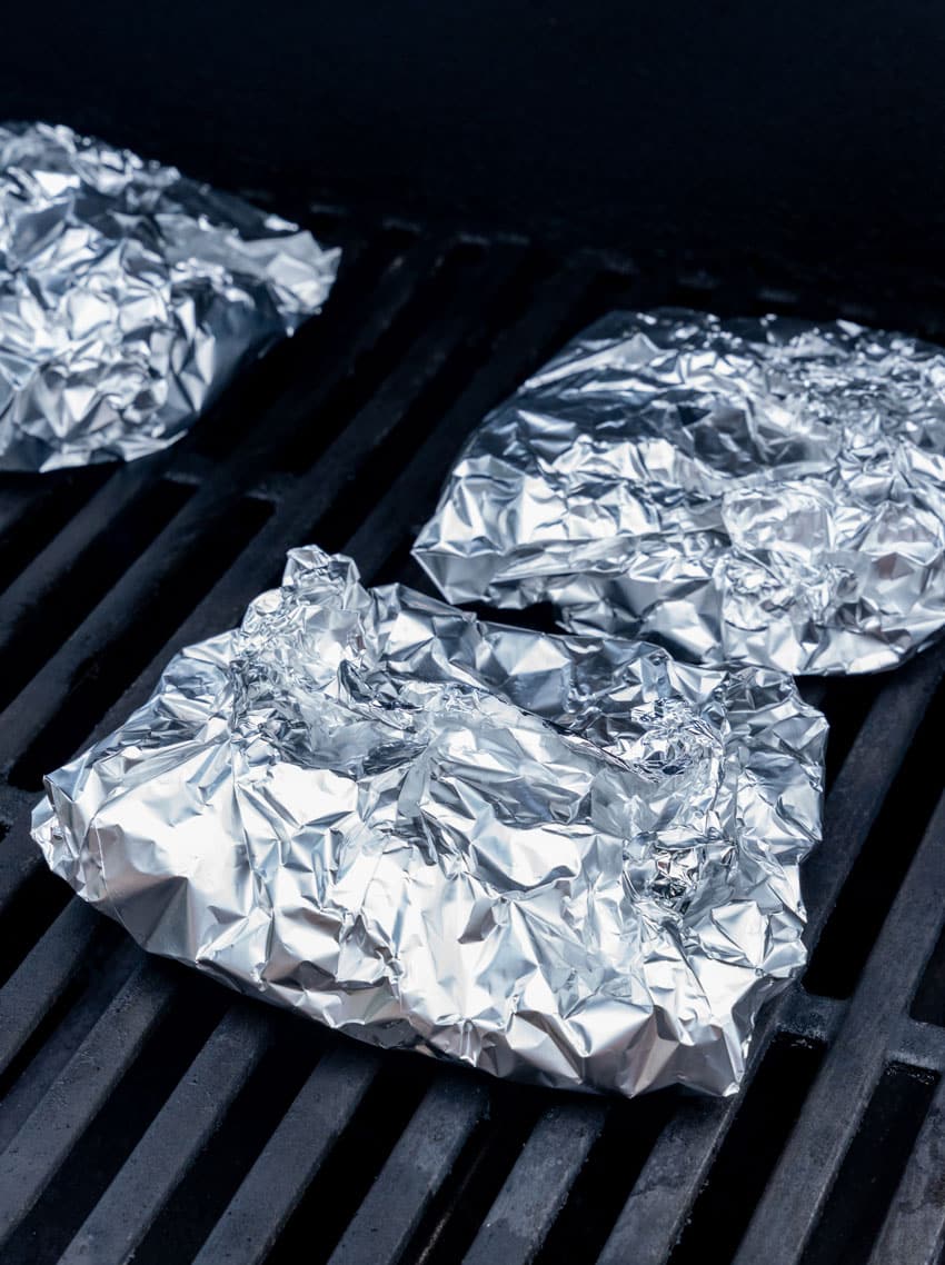 steak and potato foil packets on a grill