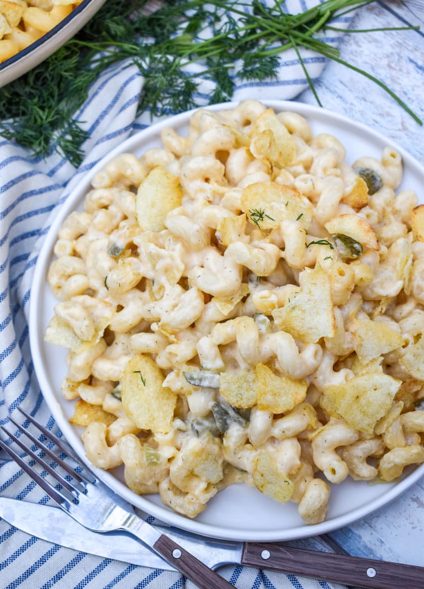 potato chip topped dill pickle macaroni and cheese on a white plate