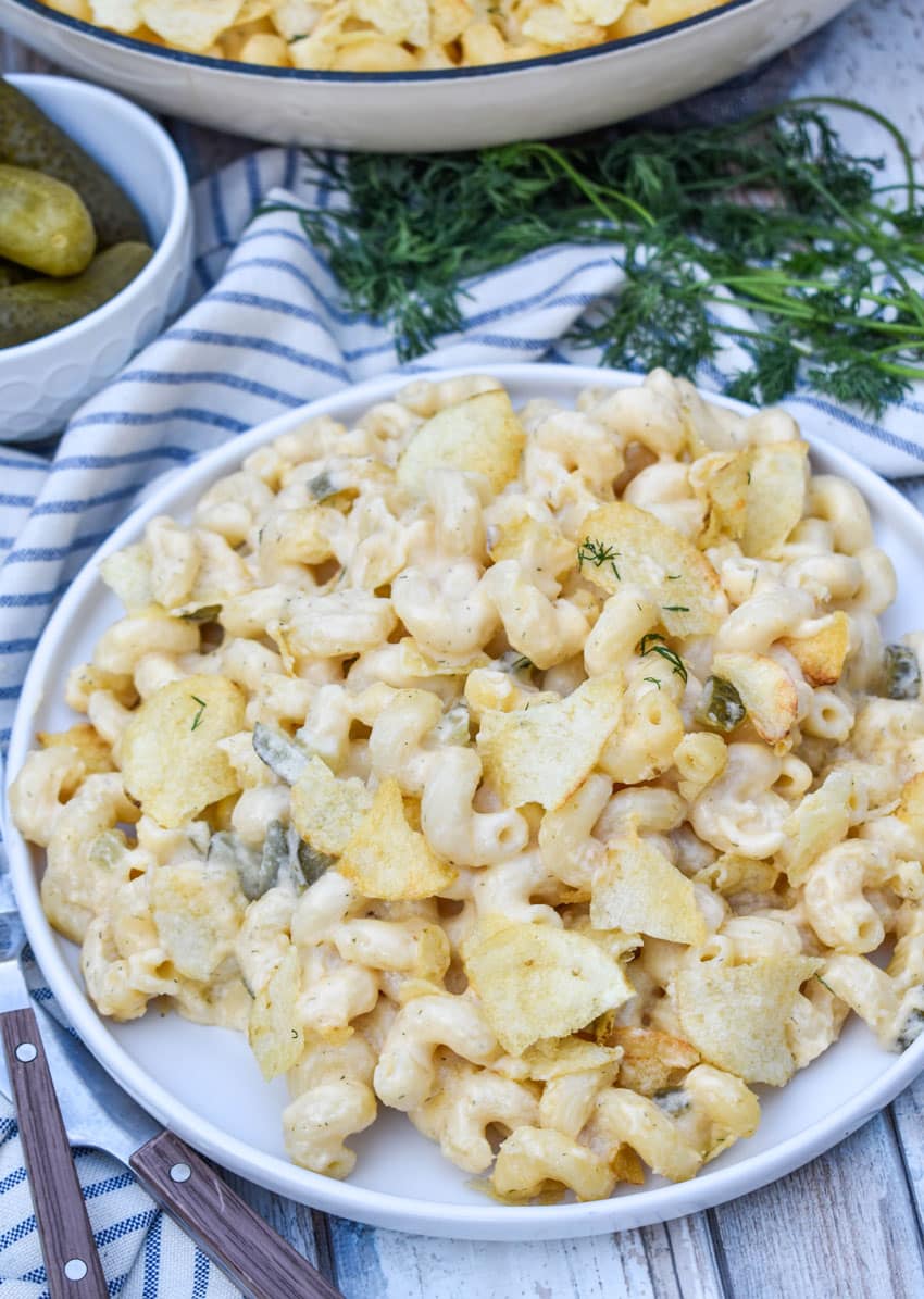 potato chip topped dill pickle macaroni and cheese on a white plate