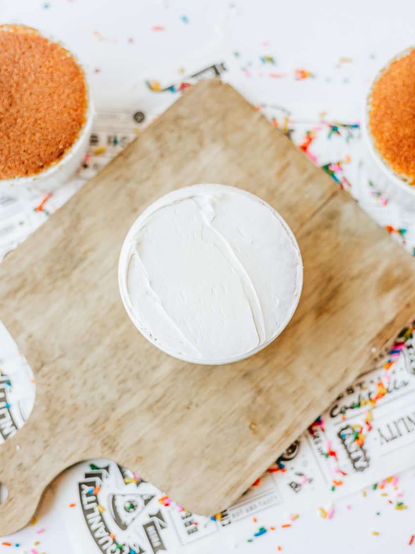 an individual frosted dot cake in a small white ramekin on a small wooden cutting board