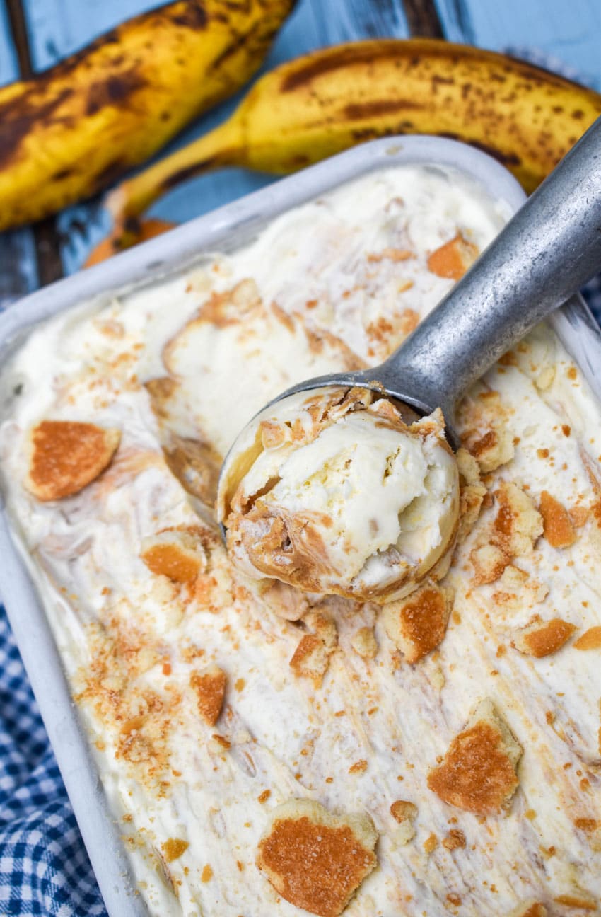 a silver ice cream scoop scooping homemade banana pudding ice cream out of a metal loaf pan