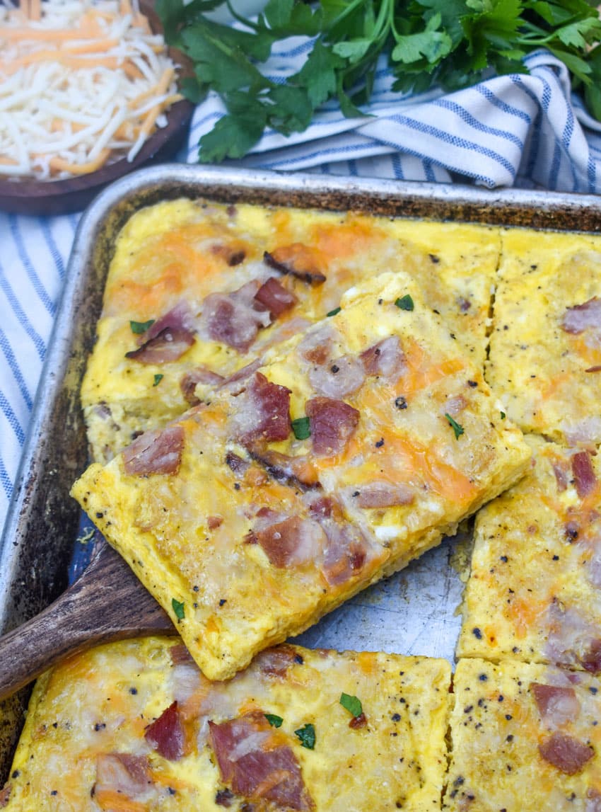 a wooden spatula lifting up a slice of sheet pan breakfast casserole